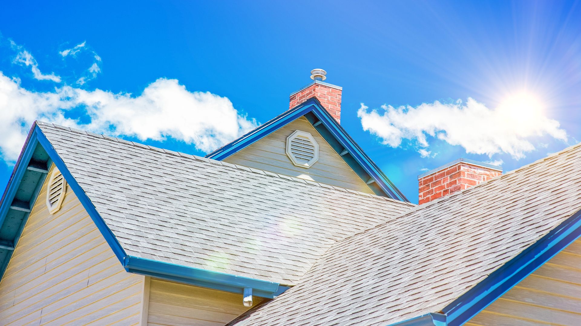 Sunny day view of house rooftops with white shingles and brick chimneys