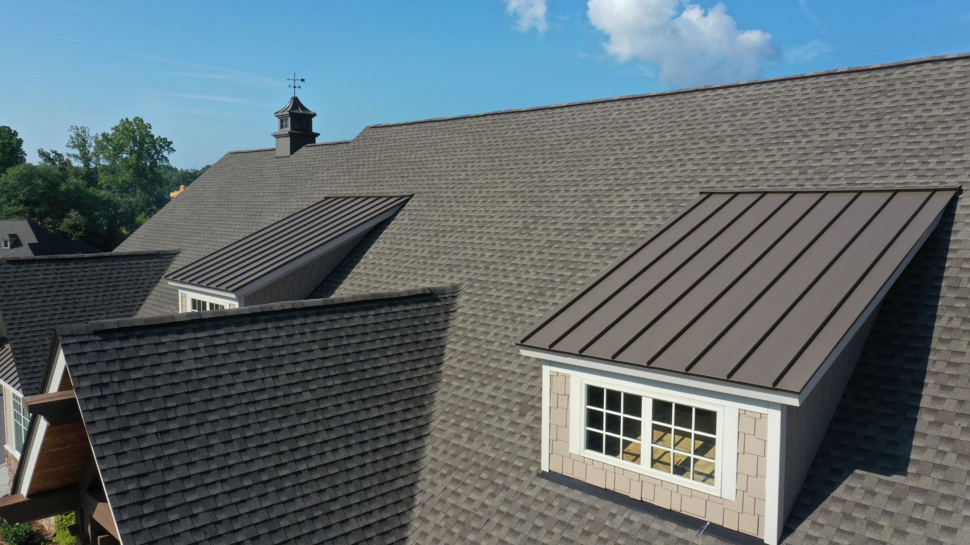 Rooftop with shingle and metal roof sections, cupola, and windows
